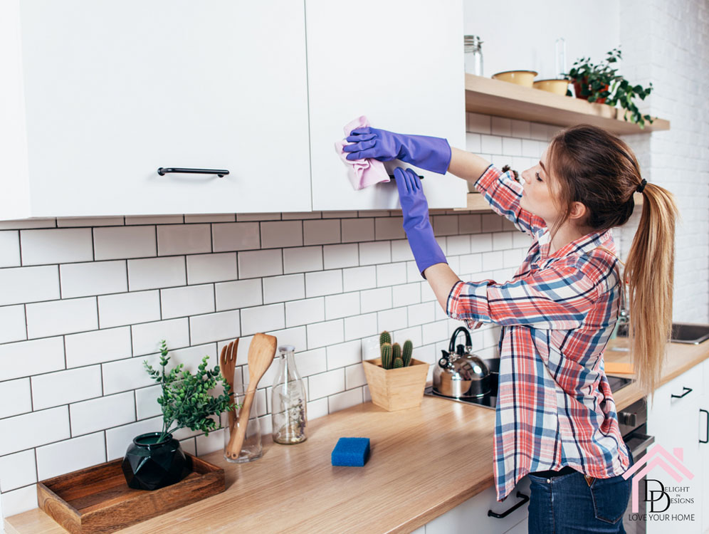 a woman cleaning a kitchen counter with a rag.