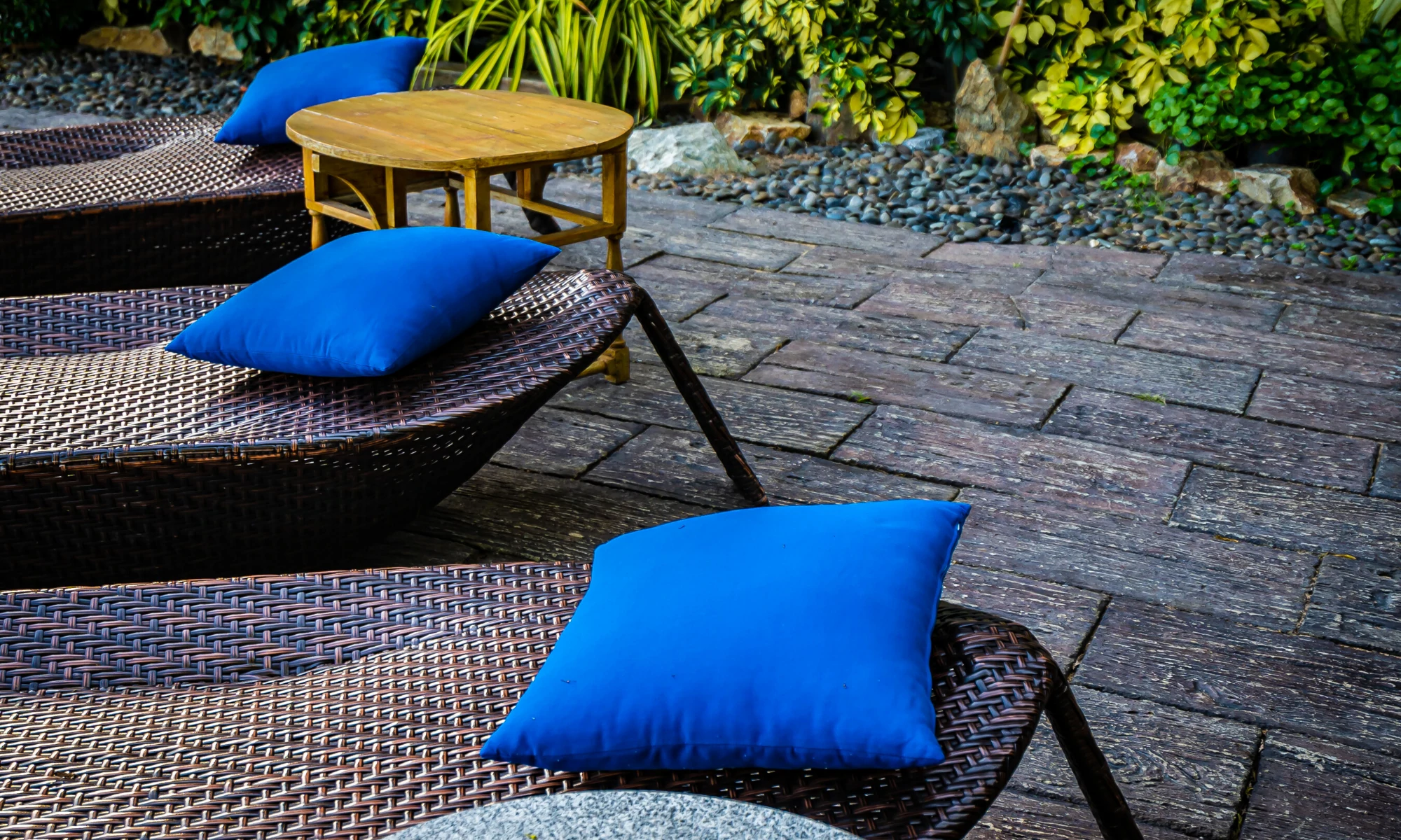 a row of wicker lounge chairs with blue cushions.