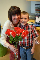 a woman and a boy holding a vase of roses.