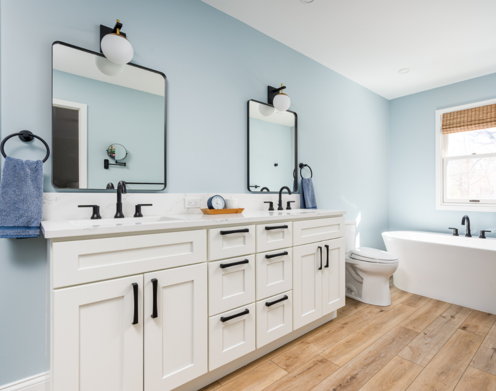 Master bathroom with a white vanity and a free standing tub. Light blue walls and square mirror with rounded edges. New Year Resolutions