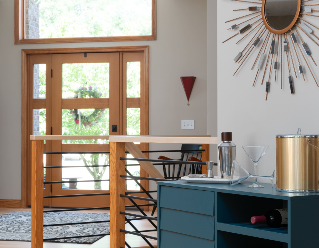 Entryway to a home with a blue cabinet for a bar an big wooden door with glass and a railing going into the basement New Year Resolutions